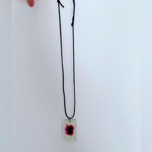 Unique resin pendant on black cord necklace, featuring a red and purple flower